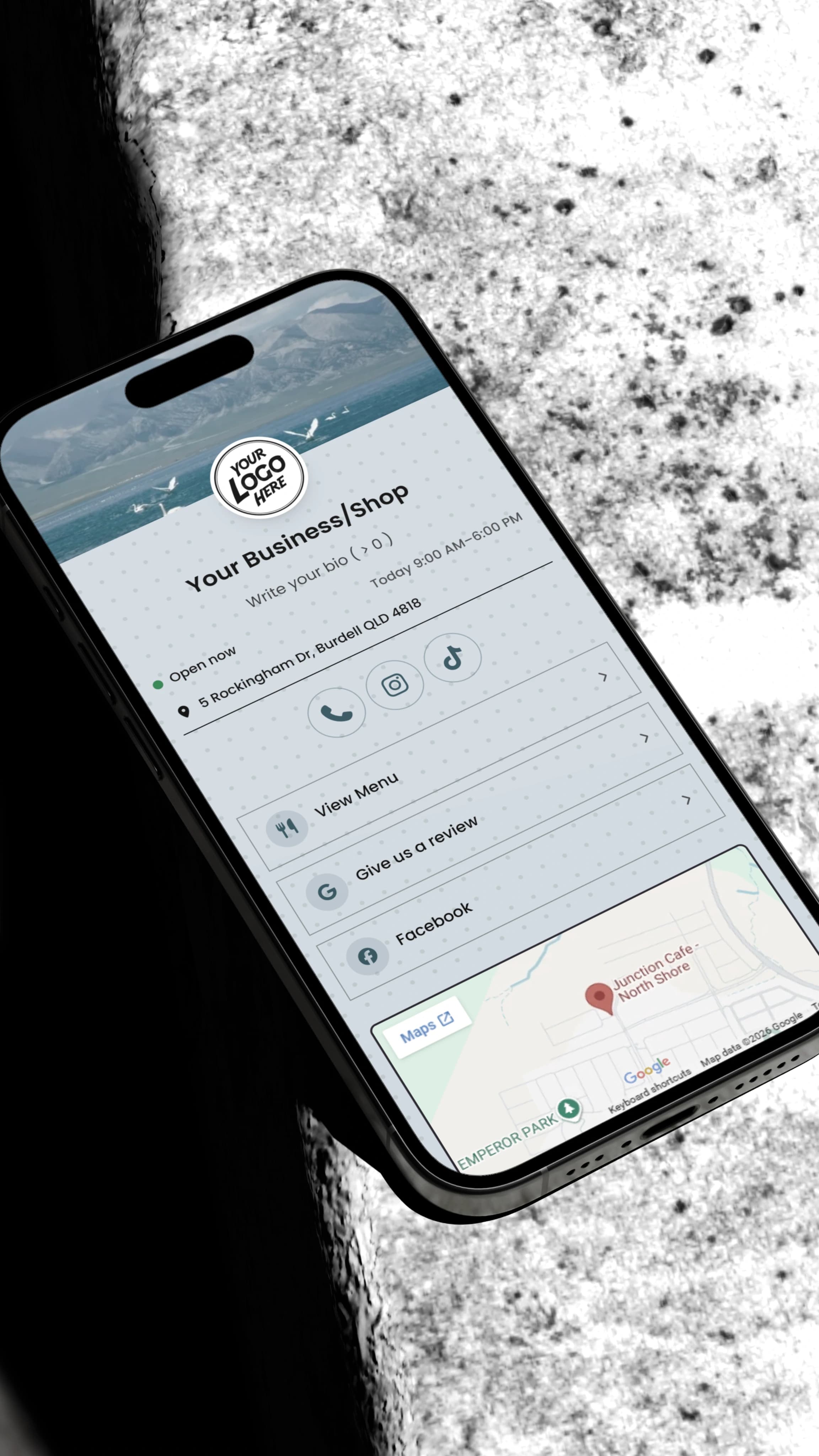 A phone showing a white BumpLnk business page beside the road